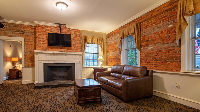 Living room with brown leather couch and wall mount television above fireplace