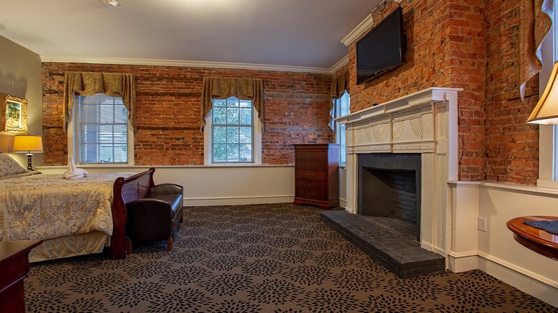 Bedroom with brick walls and television above fireplace