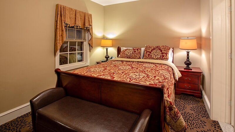 Bedroom with beige walls and red and gold comforter on bed